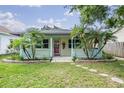 Charming home with light yellow siding, covered porch, and tropical landscaping with palm trees at 507 4Th Sw Ave, Largo, FL 33770