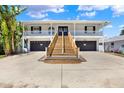 Stunning two-story home featuring dual garages, wooden stairs leading to the entrance, and a charming balcony at 5331 Bayou Grande Ne Blvd, St Petersburg, FL 33703