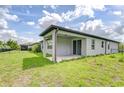 Covered patio with a sliding glass door that opens to a spacious green yard, perfect for relaxing outdoors at 6119 Bradford Woods Dr, Zephyrhills, FL 33542