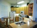 Well-lit kitchen with light wood cabinetry, matching table and chairs, and essential appliances at 6714 Dali Ave # 102, Land O Lakes, FL 34637