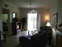 Comfortable living room with tile floors, ceiling fan, and sliding glass doors to the outdoors at 6714 Dali Ave # 102, Land O Lakes, FL 34637