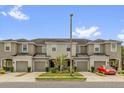 Tan townhomes with garages and a red car parked in front under a sunny blue sky at 6924 Towne Lake Rd, Riverview, FL 33578
