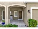 Inviting covered front porch with a brown front door, green plants, and neutral paint at 6924 Towne Lake Rd, Riverview, FL 33578
