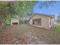 View of backyard with overgrown brush and a detached garage at 7033 Wentworth Way, New Port Richey, FL 34655