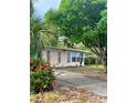 Home exterior showcasing lush trees, flowering bushes, and a concrete driveway at 72 Lake Shore Dr, Palm Harbor, FL 34684