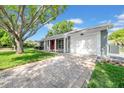 Exterior view of a single-story home with an attached garage and a brick driveway and a bright red front door at 12401 Yorktown Ln, Bayonet Point, FL 34667