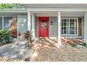 Covered front porch with brick walkway, red door, and wood trim details at 12401 Yorktown Ln, Bayonet Point, FL 34667