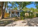 Charming blue home with a covered front porch, lush landscaping, and an inviting pergola in the front yard at 1302 E Flora St, Tampa, FL 33604