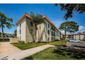 Exterior view of the condo building featuring lush lawns, mature trees and a red tiled roof at 2700 Bayshore Blvd # 2110, Dunedin, FL 34698