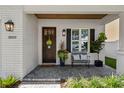 Inviting porch with a dark wood door, brick flooring, decorative plants, and a comfortable seating area at 3809 W San Pedro St, Tampa, FL 33629