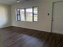 Inviting living room with dark wood-look floors, a large window, and a bright white front door at 502 Johnson Rd, Plant City, FL 33566