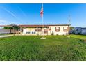Inviting single-story home featuring a well-kept lawn, covered parking, and a cozy porch with comfortable blue seating at 5409 Antigua Dr, Zephyrhills, FL 33541