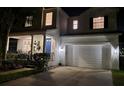 Charming two-story home with manicured lawn, two car garage and inviting blue front door at night at 7309 S Shamrock Rd, Tampa, FL 33616