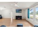 Bright living room with wood floors, a ceiling fan, a fireplace, and large windows offering natural light at 8010 Chickasaw Ln, Port Richey, FL 34668
