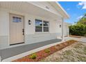 Inviting front entrance with a light-colored door, stylish lighting, and beautifully landscaped walkway at 9241 Cochise Ln, Port Richey, FL 34668