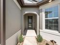 Close up of the recessed front door entry, flanked by small shrubs and accented with stone ground cover at 9271 Rally Spring Loop, Wesley Chapel, FL 33545