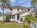 Inviting home exterior featuring a lush lawn, mature palms, and covered entryway at 1204 Rinkfield Pl, Brandon, FL 33511