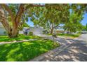 Charming one-story home featuring a lush green lawn and mature trees that provide ample shade at 1211 Stony Brook Ln, Dunedin, FL 34698