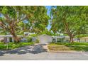 Single-story home with a well-manicured front lawn and mature shade trees at 1211 Stony Brook Ln, Dunedin, FL 34698
