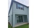 A covered back patio of a light blue home with sliding glass doors and a grassy yard at 19643 Shady Oak Dr, Land O Lakes, FL 34638