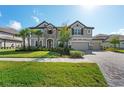 Charming home showcasing a well-manicured lawn, paver driveway, three-car garage and neutral color scheme at 33255 Kateland Dr, Wesley Chapel, FL 33545