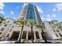 Luxury high-rise exterior featuring a modern design, blue windows, and palm tree-lined entrance against a bright blue sky at 450 Knights Run Ave # 104, Tampa, FL 33602
