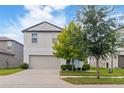 A two-story home with neutral siding, an attached garage, a well-maintained lawn, and mature trees at 6180 Spring Crayfish Ave, New Port Richey, FL 34653