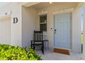 Inviting front porch with a light blue door, black rocking chair and lush greenery at 6180 Spring Crayfish Ave, New Port Richey, FL 34653