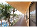 Open-air condo walkway featuring a secure entry door, offering a glimpse of community parking at 6400 46Th N Ave # 203, Kenneth City, FL 33709