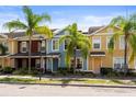 Street view of townhomes featuring colorful exteriors and lush palm trees at 7703 N Branch Ave, Tampa, FL 33604
