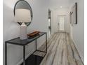 Bright hallway featuring wood floors, modern table with black frame, decor, and fresh white walls at 8812 Parsons Hill Blvd, Wesley Chapel, FL 33545