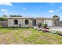 Attractive home with a stone exterior, a flower-lined walkway, and a well-kept lawn at 8918 Carmen Ln, Port Richey, FL 34668