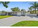 Expansive concrete driveway leading to an attached garage, complemented by a well-maintained lawn and landscaping at 94 Nicholas Dr, Dunedin, FL 34698