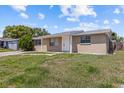 Tan single-story home with white trim, front yard, and overcast sky at 9915 Aetna Ln, Port Richey, FL 34668