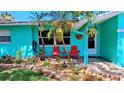 Inviting front porch featuring colorful chairs surrounded by lush plants, stone trim, and brick pavers at 12176 Croft Dr, Largo, FL 33774