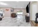 Bright and airy living room with marble floors, sleek furniture, and a sliding glass door at 1406 Valley Pl, Brandon, FL 33510