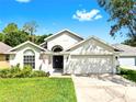 Inviting single-story home with green lawn, American flag, and a two-car garage on a sunny day at 16928 Hawkridge Rd, Lithia, FL 33547