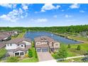 Scenic aerial view of home with a beautiful lake, fountain, and manicured landscaping at 18824 Birchwood Groves Dr, Lutz, FL 33558