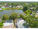 An aerial view of homes surrounding a scenic lake with mature trees and private pools in screened enclosures at 2436 Beacon Groves Blvd, Palm Harbor, FL 34683