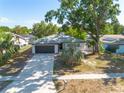 Inviting single-story home boasts a neatly manicured lawn, mature trees, and a convenient two-car garage at 2436 Beacon Groves Blvd, Palm Harbor, FL 34683