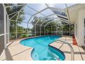 A covered swimming pool with a screen enclosure offers a view of a tranquil lake and lush greenery at 2436 Beacon Groves Blvd, Palm Harbor, FL 34683