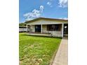 Single-story home featuring a covered porch, black railings, and lush green lawn at 5330 Jo St, Zephyrhills, FL 33542