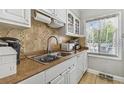The kitchen features a stainless-steel sink, tile countertops and backsplash, and white cabinets at 7523 Pitch Pine Cir # 184, Tampa, FL 33617
