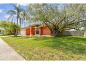 Charming single-story home with a mature tree and palm trees in the front yard at 8601 Chadwick Dr, Tampa, FL 33635