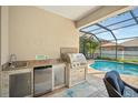 Outdoor kitchen boasts a stainless grill, sink, mini fridge, and stone counter perfect for poolside entertaining at 11429 Drifting Leaf Dr, Riverview, FL 33579