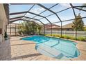Inviting screened-in pool area with a spacious brick patio, lounge chairs, and well-maintained landscaping at 11429 Drifting Leaf Dr, Riverview, FL 33579