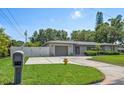 Single-story home with a driveway, lush lawn, and a white privacy fence at 13514 Oval W Dr, Largo, FL 33774