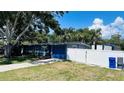 Exterior view of the home with a well-kept lawn, a driveway, a blue garage door, and a white fence at 1631 St Mary Dr, Dunedin, FL 34698