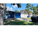 View of a home with a driveway, blue garage door, a tree, and a white fence in the background at 1631 St Mary Dr, Dunedin, FL 34698