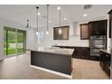 Modern kitchen with dark wood cabinets, stainless steel appliances, and a granite island with pendant lighting at 19238 Old Spanish Rd, Tampa, FL 33647